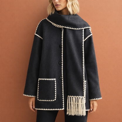 Grijze elegante damesjas met ruime pasvorm en bijpassende sjaal, ideaal voor stijlvolle outfits tijdens koude dagen.