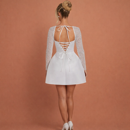 Witte elegante mini jurk voor dames met lange mouwen en glanzende uitstraling, perfect voor feestelijke gelegenheden.